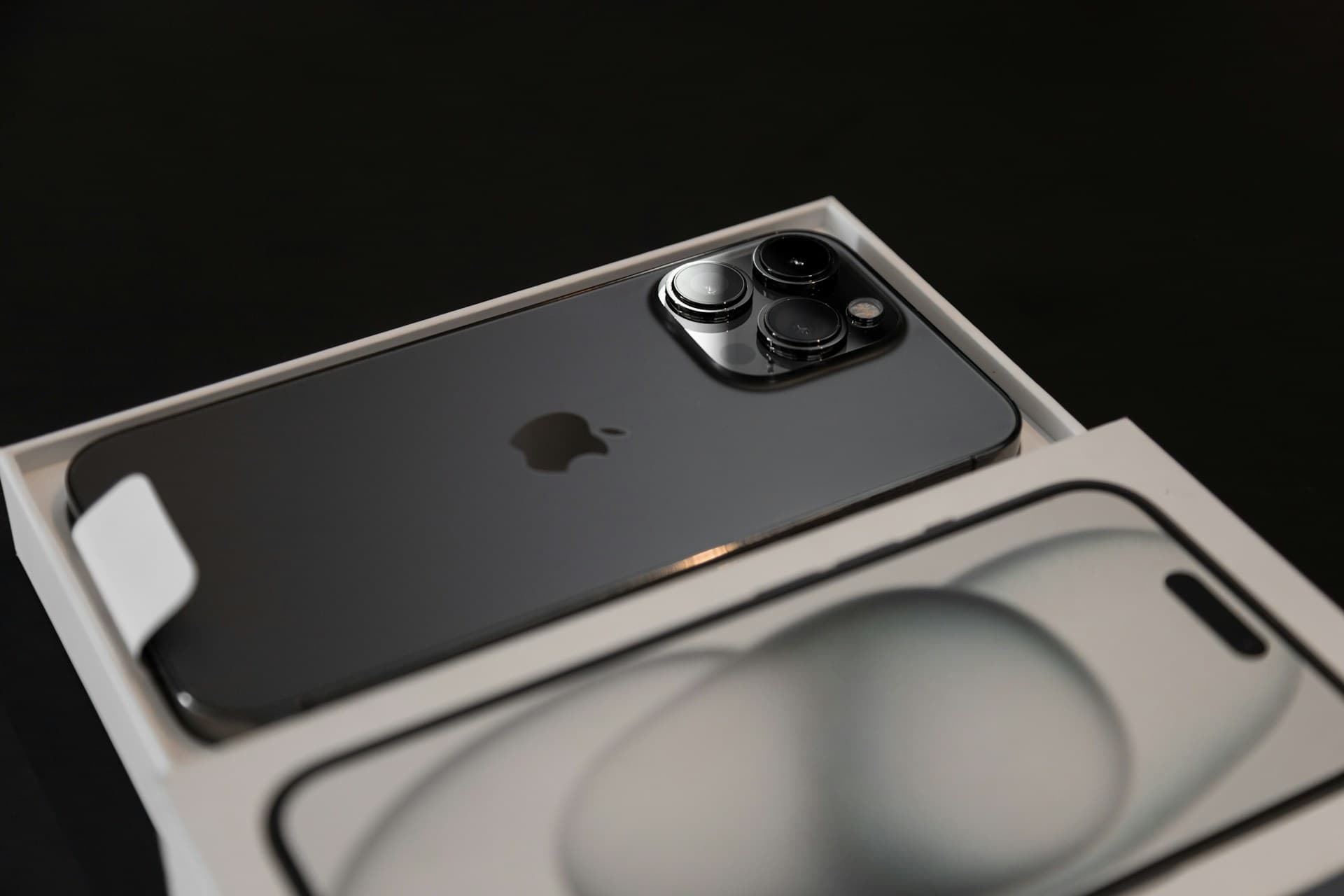 A new iPhone in its opened box on a dark surface