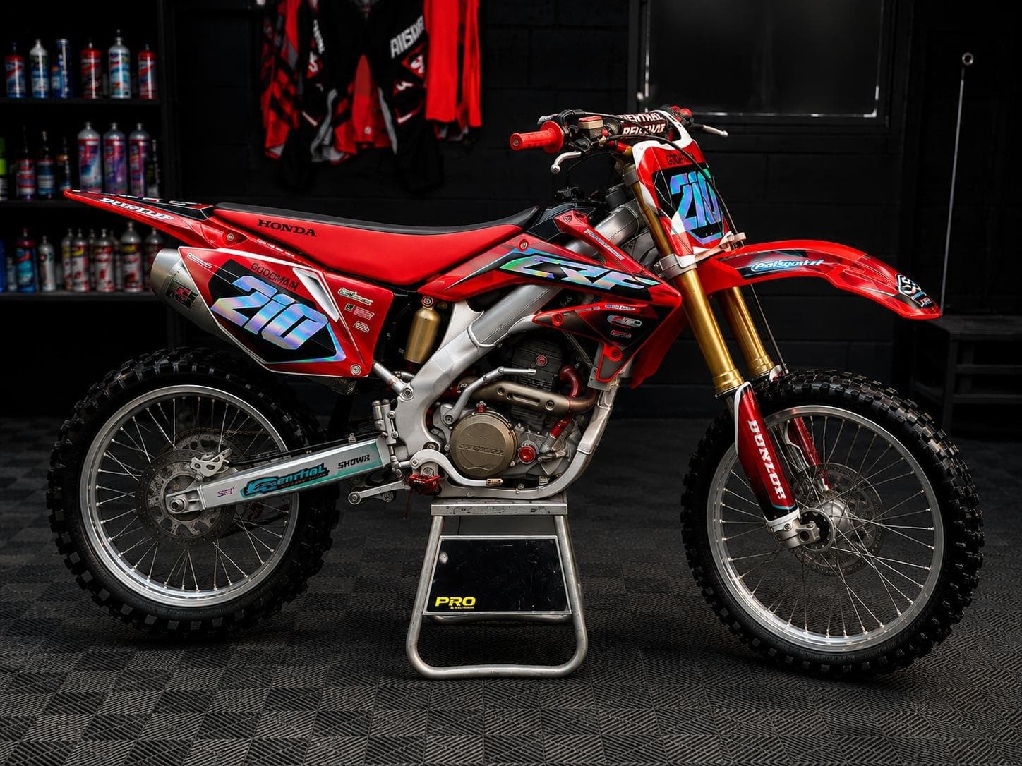 The Honda CRF 250 side on, on a paddock stand in a black garage